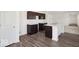 Modern kitchen with dark wood cabinets, white countertops, and a center island, next to a spacious living room at 4712 E Shadowbrook Dr, Camby, IN 46113