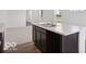 Kitchen island featuring dark cabinets, a white countertop, and a stainless steel sink, in a modern, open space at 4712 E Shadowbrook Dr, Camby, IN 46113