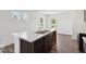 Kitchen island with stainless steel sink, dark wood cabinets and bright, modern floors and walls at 4712 E Shadowbrook Dr, Camby, IN 46113