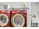 Laundry room featuring two red Samsung washing machines, a utility sink, and shelving at 5226 E St Clair St, Indianapolis, IN 46219