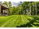 Spacious backyard with lush green lawn, covered patio, and wooded perimeter, offering privacy at 552 E 82Nd St, Indianapolis, IN 46240