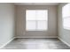 Neutral room featuring gray wood-look flooring, white trim, and two windows at 5786 Blue Sky Dr, Whitestown, IN 46075