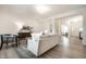 Open-concept living room with a view to the kitchen and entry. Hardwood floors, neutral sofa and a plush chair at 647 Albermarle Dr, Pittsboro, IN 46167