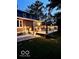 Well lit backyard deck and backyard at dusk, featuring stairs to the yard and manicured landscaping at 6820 W Forest Brook Dr, Fountaintown, IN 46130