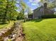 Spacious backyard featuring lush green grass, mature trees, a creek, and fenced-in area at 6820 W Forest Brook Dr, Fountaintown, IN 46130