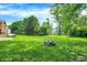 A spacious backyard features a cozy fire pit, lush green lawn, and mature trees for serene outdoor living at 8315 San Marcos Cir, Indianapolis, IN 46256