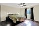 Cozy bedroom with dark wood floors, a ceiling fan, modern lamps and stylish black-out curtains at 8315 San Marcos Cir, Indianapolis, IN 46256