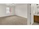 Bright bedroom with neutral carpet, white walls, window, and a view into the bathroom at 8920 Hunters Creek Dr # 101, Indianapolis, IN 46227
