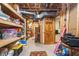 Unfinished basement storage area with wood shelves and exposed pipes, along with a doorway to another room at 10937 Sawgrass Dr, Fishers, IN 46037