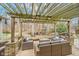 Outdoor patio area with wicker furniture, a stone base, overhead pergola, and a view of the landscaped backyard at 10937 Sawgrass Dr, Fishers, IN 46037