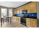 Efficient kitchen with light wood cabinetry, black appliances, and a cozy dining area at 11046 Timberview Dr, Fishers, IN 46037