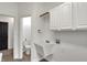 Well-lit laundry room featuring white cabinetry, utility sink, and wood-look flooring at 12618 E 86Th St, Indianapolis, IN 46236