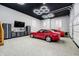 Spacious garage featuring two classic red cars, custom lighting and organized storage solutions at 14577 Faucet Ln, Fishers, IN 46040