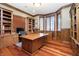 Home office with built-in bookshelves, rich wood trim, multiple windows, and a classic hardwood floor at 14577 Faucet Ln, Fishers, IN 46040