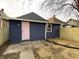 Exterior view of a home's backyard featuring blue siding and a charming pink door at 1518 Lawton Ave, Indianapolis, IN 46203