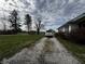 Long gravel driveway leading to a white home and garage, bordered by lush green lawns and mature trees at 3179 W 400 N, Fairland, IN 46126
