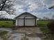 Spacious two-car garage with a concrete slab and metal support, surrounded by a vast green field and trees at 3179 W 400 N, Fairland, IN 46126