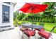 Outdoor patio with table, chairs, red umbrella, and firepit surrounded by a plush green lawn and mature trees at 3641 Shady Lake Dr, Westfield, IN 46074