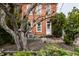 Charming red brick home featuring a white front door, mature trees, and professional landscaping at 424 E Vermont St, Indianapolis, IN 46202