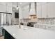 Spacious kitchen featuring an island with sink, stainless steel appliances, stone backsplash, and sleek white cabinets at 5123 Oak Ridge Pl, Columbus, IN 47201