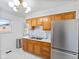 Well-lit kitchen with stainless steel refrigerator, wooden cabinets and marble tile flooring at 5240 Magnolia Dr, Columbus, IN 47203