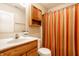Bathroom featuring a toilet, a cabinet and a sink with orange and tan stripped curtain at 6145 Crystal View Dr, Indianapolis, IN 46237
