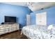 A blue bedroom is furnished with a dresser and tv and has hardwood floors and a ceiling fan at 6145 Crystal View Dr, Indianapolis, IN 46237