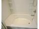 A clean, white bathtub with tile surround and built-in shelving offers a relaxing bathing experience at 6418 W Oxford Ln, McCordsville, IN 46055