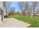 Spacious backyard featuring a concrete patio, large grassy area, mature trees and a swing set at 6733 Dorchester Dr, Zionsville, IN 46077