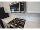 Close-up of stainless steel microwave and cooktop set in white cabinets and a white tile backsplash at 8194 Bostic Ct, Fishers, IN 46038