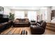 Inviting living room featuring hardwood floors, a leather sofa, and natural light from the bright windows at 8194 Bostic Ct, Fishers, IN 46038