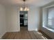 Dining room featuring wood floors, a modern light fixture, and a view into the kitchen with white cabinets and black appliances at 937 N Bosart Ave, Indianapolis, IN 46201