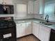 Contemporary kitchen featuring white cabinets, granite countertops, black appliances, and modern fixtures at 937 N Bosart Ave, Indianapolis, IN 46201