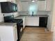 Modern kitchen with white cabinets, granite countertops, black appliances, and wood floors at 937 N Bosart Ave, Indianapolis, IN 46201