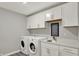 Functional laundry room with white cabinets, sink, and modern washer and dryer appliances at 10237 Sand Run Ln, Fortville, IN 46040