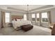 Spacious primary bedroom boasts natural light from large windows, tray ceilings, and modern chandelier at 10237 Sand Run Ln, Fortville, IN 46040