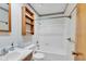 Bright bathroom featuring a tub/shower, toilet, single sink, and shelving unit for storage at 1330 N Gibson Ave, Indianapolis, IN 46219