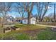 Spacious backyard with garden beds, gravel patio, and a detached garage surrounded by trees and greenery at 136 W 43Rd St, Indianapolis, IN 46208