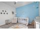 Bedroom with a crib, chair, and blue accent wall featuring ocean-themed decor at 16566 Branham Dr, Fishers, IN 46040