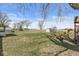 Large backyard with mature trees, an old playground slide, and shed with a sprawling grass-covered field at 1710 Bittersweet Dr, Anderson, IN 46011