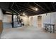 Basement with exposed ductwork, white painted walls, concrete floor, and small dining table at 2352 N College Ave, Indianapolis, IN 46205
