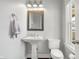 Well-lit half bathroom features a classic pedestal sink and a framed mirror at 2352 N College Ave, Indianapolis, IN 46205