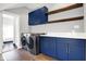Bright laundry room features blue cabinets, stainless steel washer and dryer, and open shelving at 2352 N College Ave, Indianapolis, IN 46205