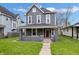 Charming two-story home boasts a freshly cut lawn and a welcoming red door at 2748 Carrollton Ave, Indianapolis, IN 46205