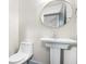 Cozy powder room features a pedestal sink, a round mirror and modern fixtures at 2748 Carrollton Ave, Indianapolis, IN 46205