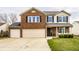 Inviting two-story brick home featuring an attached two-car garage and well-manicured front lawn at 305 Beacon Point Ln, Fortville, IN 46040
