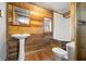 Rustic bathroom featuring wood-paneled walls, a pedestal sink, and toilet at 3721 S 575 W, Trafalgar, IN 46181