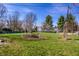 Green backyard with trees, garden beds, and a clear blue sky at 3926 Rookwood Ave, Indianapolis, IN 46208