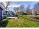 Large grassy backyard with a small patio, garden, and a purple building in the distance, surrounded by trees at 3926 Rookwood Ave, Indianapolis, IN 46208