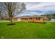 Exterior side view of a red brick home with a green lawn, landscaping, and a tree in the front at 3929 Lee St, Anderson, IN 46011
